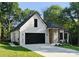 Charming white brick home with a black garage door, wood columns, professional lighting, and manicured landscaping at 1622 Burtonwood Cir, Charlotte, NC 28212
