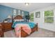 Bright bedroom featuring a wooden bed frame, blue accent wall, and two windows offering natural light at 183 Canoe Pole Ln, Mooresville, NC 28117