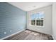 A serene bedroom with blue accent wall, wood-look floors and a bright window at 1986 Trace Creek Dr, Waxhaw, NC 28173