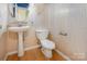 Small bathroom with a pedestal sink, standard toilet, and white beadboard paneling at 2001 Enderbury Dr, Indian Trail, NC 28079