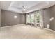 Spacious main bedroom featuring a tray ceiling, ceiling fan, and three windows with decorative curtains at 2001 Enderbury Dr, Indian Trail, NC 28079