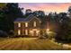 Elegant brick home at twilight, featuring warm interior lighting and landscaped front yard at 205 Rosedale Ln, Matthews, NC 28105