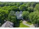 Aerial view of white home surrounded by lush, mature trees with a long driveway at 2324 Kingsmill Ter, Charlotte, NC 28270