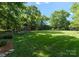 Beautifully landscaped backyard with green grass, trees, a playset, and fencing at 2324 Kingsmill Ter, Charlotte, NC 28270