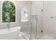 Bathroom with a glass-enclosed shower, soaking tub, large window with wooded view, and tiled floors at 3011 Mckee Rd, Charlotte, NC 28270