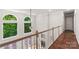 Bright hallway with hardwood floors, a wooden banister, arched windows, and natural light at 3011 Mckee Rd, Charlotte, NC 28270
