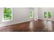 Living room featuring gleaming hardwood floors, large windows with green views, and access to an outdoor deck at 3011 Mckee Rd, Charlotte, NC 28270