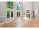 Bright living room with soaring windows, light wood floors, fireplace, and access to a deck at 3011 Mckee Rd, Charlotte, NC 28270