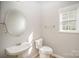 Bright half bathroom with a large round mirror, toilet, sink and a window at 5805 Lindley Crescent Dr, Indian Trail, NC 28079
