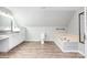 Bright bathroom with wood floors, white walls, soaking tub and vanity at 6811 Kluttz Rd, Concord, NC 28025