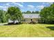 Charming single-story home with a covered porch and lush landscaping, framed by mature trees at 6811 Kluttz Rd, Concord, NC 28025