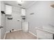 Functional laundry room featuring tiled floors, storage cabinets, utility sink and modern gray wall paint at 6811 Kluttz Rd, Concord, NC 28025