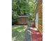 View of a backyard with a wooden shed, adjacent to a yellow home, accented by a rustic fence and trees at 6832 Delta Lake Dr, Charlotte, NC 28215