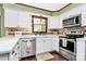 Well-lit kitchen featuring white cabinets, stainless steel appliances, and hardwood floors at 7020 Leesburg Rd, Charlotte, NC 28215