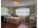 Light-filled bedroom with hardwood floors, floral bedding, and sheer curtains at 708 East St # 89, Albemarle, NC 28001