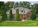 Charming brick home with manicured lawn and tall evergreens in a beautifully landscaped front yard at 803 Woodmoore Ln, Kannapolis, NC 28081
