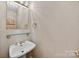 Compact powder room with a pedestal sink, mirror, and decorative sconces at 803 Woodmoore Ln, Kannapolis, NC 28081