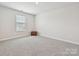 Clean, carpeted bedroom with a small brown bench underneath a window at 835 Windage Way, Pineville, NC 28134