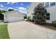 A spacious driveway leads to a detached garage next to the home, with mature landscaping at 8702 Aspinwall Dr, Charlotte, NC 28216