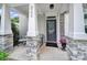 Inviting front porch featuring stone columns, seating, and a welcome mat at 8702 Aspinwall Dr, Charlotte, NC 28216