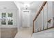 Bright foyer with light-colored tile flooring, white door, and staircase with wooden handrail at 9728 Blossom Hill Dr, Huntersville, NC 28078