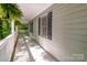 View down the covered porch with painted floor and railing and natural fern hanging from the roof at 1118 Brookwood Dr, Stanley, NC 28164