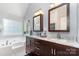 Bathroom featuring a double sink vanity with marble countertop and a large tub by the window at 11624 Crossroads Pl, Concord, NC 28025