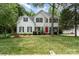 Charming two-story home with a well-manicured lawn, red front door, and mature landscaping, in a quiet neighborhood at 11624 Crossroads Pl, Concord, NC 28025