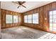 Living room with wood paneled walls, neutral carpeting, and natural light from three windows at 1280 Queensgate St, Gastonia, NC 28054