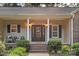 Inviting front porch with classic columns and seating, framing a decorative front door and lush landscaping at 1313 Western Hills Ln, Vale, NC 28168