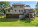 Backyard view with a deck, stairs, partial brick foundation and lush green grass at 1701 Whitney Ln, Salisbury, NC 28146