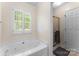 A well-lit bathroom with a soaking tub, a glass-enclosed shower and a large window at 1701 Whitney Ln, Salisbury, NC 28146