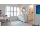 Sunlit bedroom with a white dresser and desk, complemented by sheer curtains and a stylish mirror, plus ensuite bath at 2008 Thatcher Way, Fort Mill, SC 29715