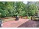A wooden deck with red railings and a grill offers an outdoor space surrounded by lush, mature trees at 2012 Killarney Pl, Charlotte, NC 28262