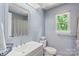 Bathroom with a white vanity, framed mirror, and soft blue walls is brightened by a sunlit window at 2012 Killarney Pl, Charlotte, NC 28262