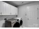 This modern laundry room includes sleek gray and white appliances and white cabinets for storage at 2026 Rosewater Ln, Indian Trail, NC 28079