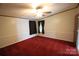 A simple bedroom with a ceiling fan and red carpet, featuring two windows covered with curtains at 220 Singing Pine Dr, Clover, SC 29710