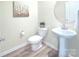 Powder room with a pedestal sink, toilet, round mirror and art on the wall at 240 Orson Oaks Ln, Pineville, NC 28134