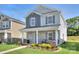 Attractive two-story home with stone veneer, a cozy front porch, and a lush green lawn at 240 Orson Oaks Ln, Pineville, NC 28134