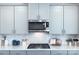 Close up on gas stovetop with light gray cabinets, subway tile backsplash and stainless steel microwave at 240 Orson Oaks Ln, Pineville, NC 28134