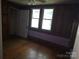 Spacious bedroom featuring wood paneling, hardwood floors, two windows, and an open closet at 29 Willow St, Badin, NC 28009