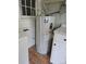 Close-up of a hot water heater, positioned near a washing machine and white cabinetry, set within a laundry space at 29 Willow St, Badin, NC 28009
