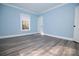Open bedroom shows light blue walls, natural light, and sleek gray plank flooring at 305 E Henry St, Belmont, NC 28012