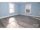 Bright bedroom with two windows, light blue walls, and modern gray plank flooring at 305 E Henry St, Belmont, NC 28012