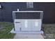 Exterior shot of a gray HVAC unit sitting on a concrete slab, backed by a dark brick exterior wall with a window at 305 E Henry St, Belmont, NC 28012