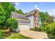 View of the home's side facade showing the garage, brick accents, and manicured greenery at 5238 Downing Creek Dr, Charlotte, NC 28269