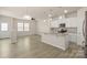 Open living space with wood floors, bright lighting, and view into modern kitchen at 5337 Orchid Bloom Dr, Indian Land, SC 29707