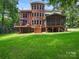 Rear view of brick home with a deck and screened porch overlooking a spacious yard at 610 Hampshire Hill Rd, Matthews, NC 28105