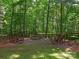 Outdoor stone fire pit and sitting area surrounded by mature trees at 610 Hampshire Hill Rd, Matthews, NC 28105