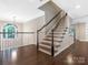 Foyer featuring hardwood floors, stairs with dark banister and white spindles, and a half-moon window at 610 Hampshire Hill Rd, Matthews, NC 28105
